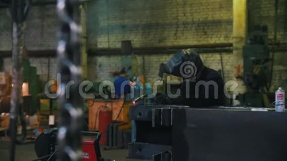 建筑工厂一名工人在头盔中使用焊机一条挂在前景上的链子视频的预览图