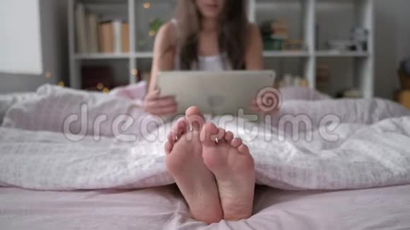 科技互联网和人的概念幸福的年轻女子躺在床上平板电脑在家里的卧室里视频的预览图