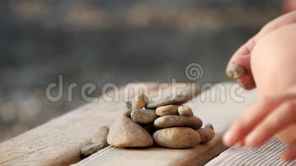 一个孩子在海边的木架上玩石头特写把相机对准孩子手视频的预览图