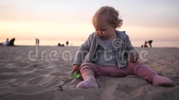 小卷曲的女孩在沙滩上玩一把铲子在海边散步视频的预览图