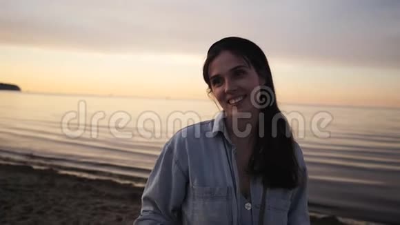 美丽的年轻女子在海边的夕阳下微笑着交谈视频的预览图