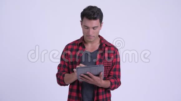 年轻的西班牙裔时髦男人在使用数码平板电脑时思考问题视频的预览图