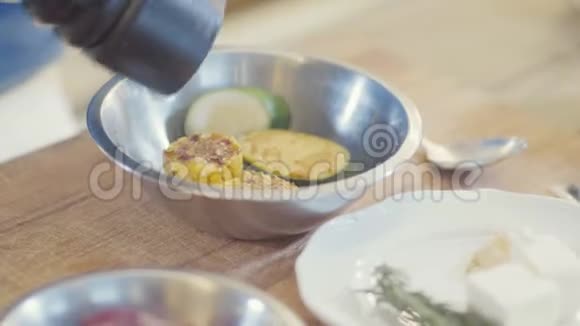 厨师戴着黑色手套在金属板上加入盐上面有西葫芦和玉米片关门视频的预览图