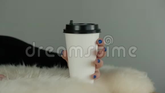 一个蓝色指甲的年轻女孩优雅的手拿着一个纸咖啡杯视频的预览图