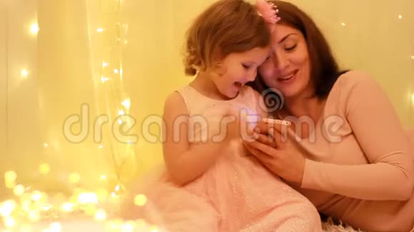 妈妈和女儿在智能手机上玩应用程序孩子和妈妈玩手机游戏视频的预览图