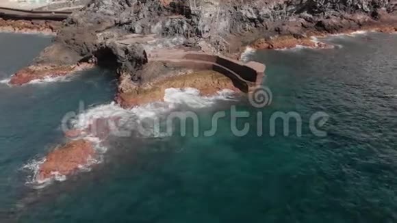 空中射击圆形飞行在岩石火山海岸的高速蓝色的海浪在周围跳动在视频的预览图