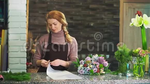 一个穿着围裙的女花店站在花店的柜台上包着一束花视频的预览图
