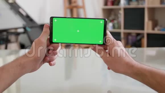 男人的视角水平手持一部绿色屏幕的智能手机视频的预览图