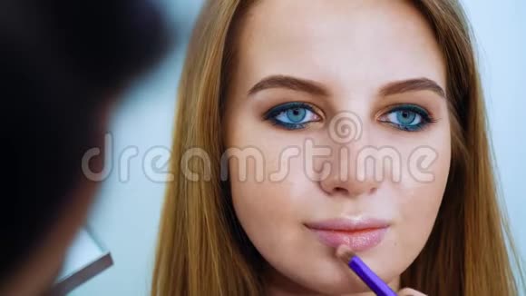 化妆师在美容院为蓝眼睛红发的可爱女孩化妆视频的预览图