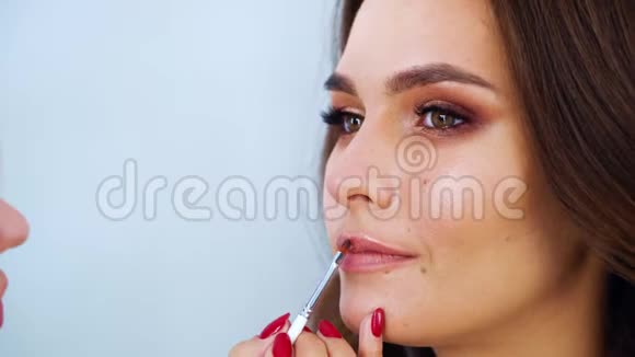 由化妆师亲手在美容院做唇彩的年轻可爱唇彩的特写视频的预览图