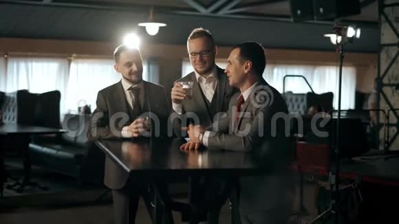一队身着西装的商人在酒吧里聊天喝着威士忌庆祝成功视频的预览图
