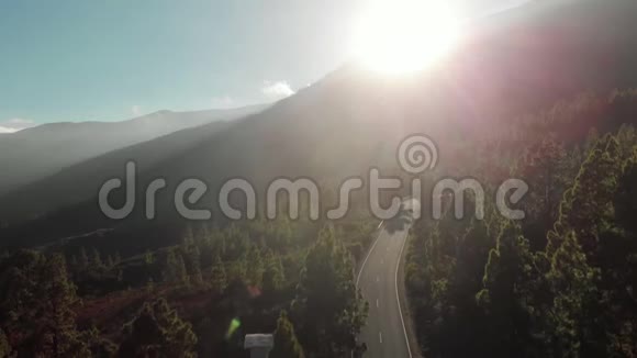 空中射击摄像机向下移动在山上日落时蜿蜒的山路蜿蜒曲折视频的预览图