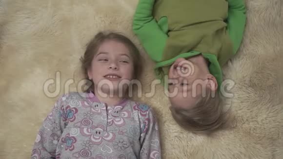 穿着睡衣的可爱的孩子们躺在地板上地毯蓬松哥哥和姐姐在一起玩得很开心快乐视频的预览图
