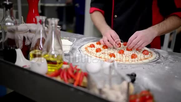餐厅厨房厨师把奶酪和西红柿放在披萨上面视频的预览图