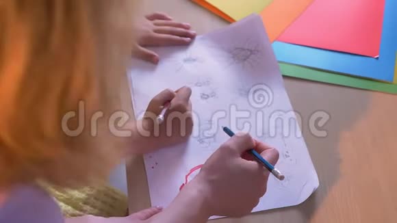 妈妈和她的孩子一起在纸上画画或者做美术作业坐在家里的桌子旁视频的预览图