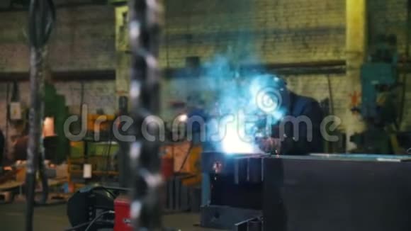 建筑工厂戴着头盔的人使用焊接机一条挂在前景上的链子视频的预览图