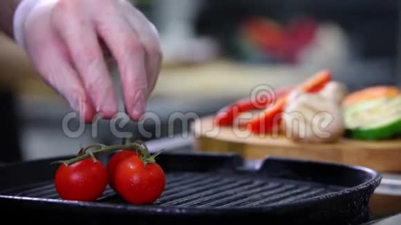 在厨房工作的厨师把煎好的西红柿从木桌上的平底锅放到另一种蔬菜上视频的预览图