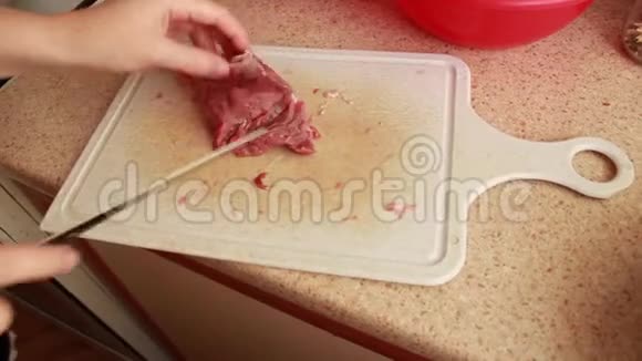 女孩在木板上用刀切肉准备烹饪食物视频的预览图