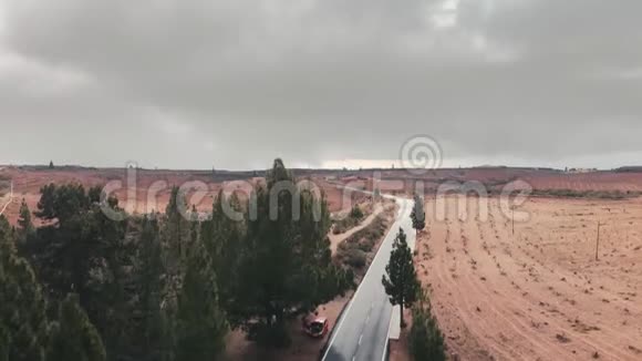 空中射击汽车沿着柏油路行驶在绿树和红树的映衬下向远处延伸视频的预览图