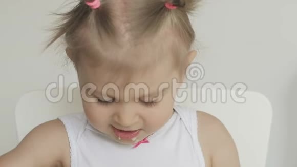 一个小女孩坐在孩子们桌子旁用勺子吃粥视频的预览图