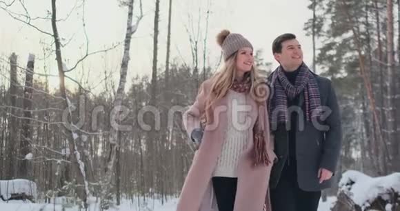 年轻的夫妇走过冬天的森林一男一女看着对方笑得很慢视频的预览图