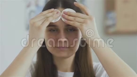 美丽的女人用棉垫洗脸看着相机视频的预览图