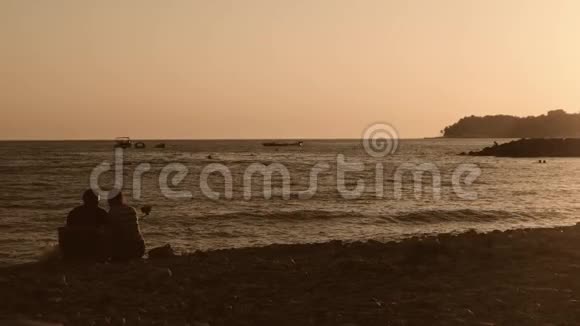 在五颜六色的日落背景下海滩上的浪漫情侣视频的预览图
