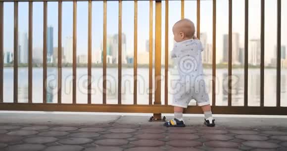 跳舞的快乐的欧洲男孩在篱笆边上保持着栏杆站着跳舞看着视频的预览图