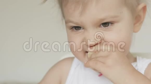 坐在白色儿童桌旁吃香蕉的可爱小女孩视频的预览图