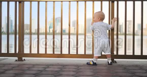 跳舞的快乐的欧洲男孩在篱笆边上保持着栏杆站着跳舞看着视频的预览图