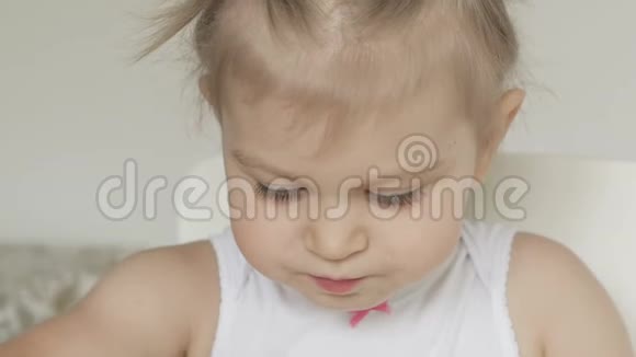 坐在白色儿童桌旁吃香蕉的可爱小女孩视频的预览图
