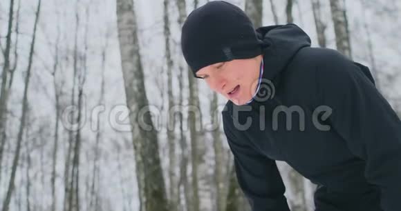 一个年轻人在冬天的森林里晨跑累了停下来休息继续跑他恢复了体力视频的预览图