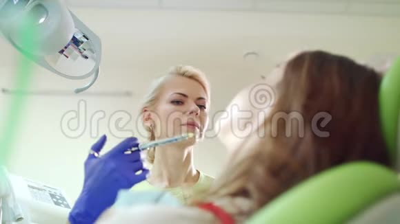 在生病的牙齿里注射麻醉剂女性口腔医生视频的预览图