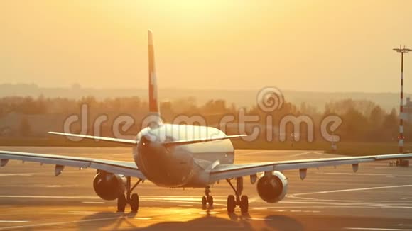 一架巨大的飞机正在橙色日落背景下的机场跑道上移动视频的预览图