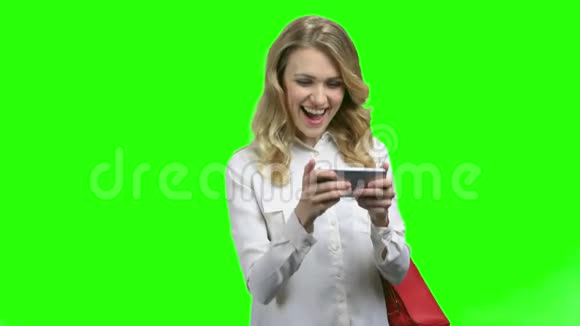 兴奋的女人在绿色屏幕背景下使用智能手机视频的预览图