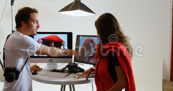 男性摄影师在电脑4k上向女性模特展示照片视频的预览图