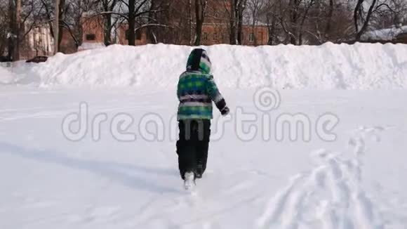 男孩在雪地里玩耍跑着爬在高高的雪地上视频的预览图