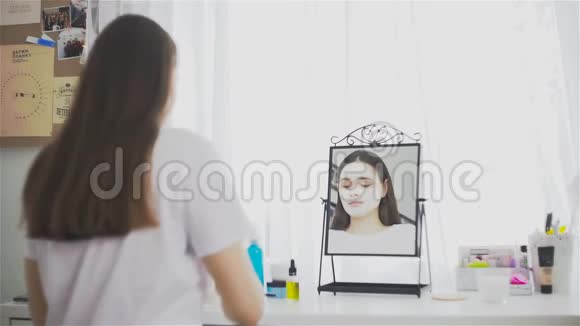 在镜子前的房间里戴化妆面具的女人视频的预览图