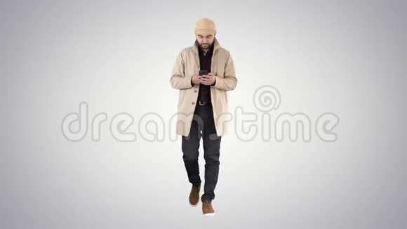 穿斗篷的帅哥在梯度背景下在手机上行走和发短信视频的预览图