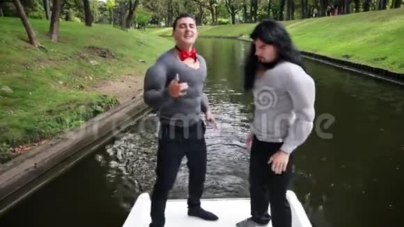两个穿着假肌肉服装的有趣男子在船上唱歌跳舞视频的预览图