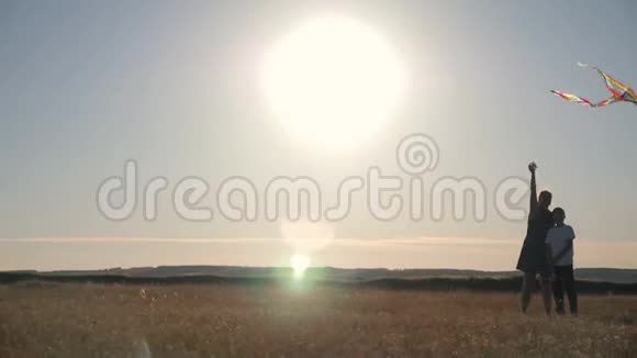 妈妈和儿子在日落时在田野里放风筝视频的预览图