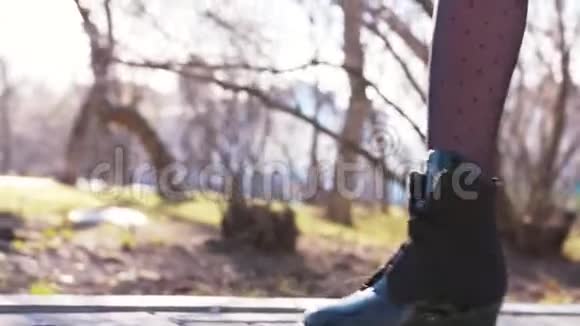 春天美丽的女人穿着黑色的高脚靴和紧身衣在公园里和树木一起走在路上视频的预览图