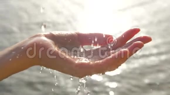 女人手在海景背景上玩饮料水滴女性用杯状的手上面滴着水视频的预览图