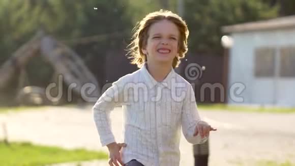 金色可爱的小男孩在夏日奔跑微笑的肖像在公园花园外玩得开心的孩子视频的预览图