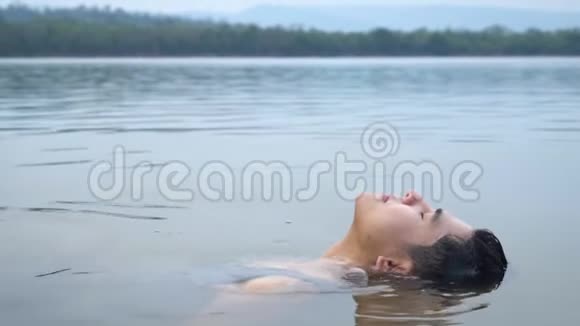 一个漂亮的亚洲人在水里漂浮慢动作视频的预览图