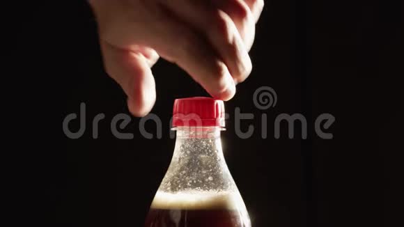 男人打开塑料瓶泡沫可乐在黑色背景下视频的预览图