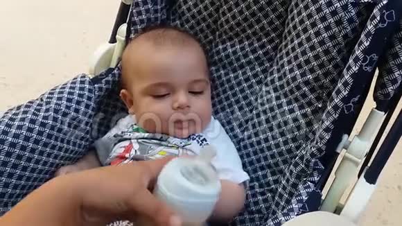 可爱的小男孩在轮椅上喝着瓶子里的牛奶视频的预览图