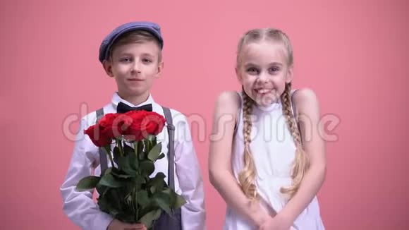 微笑的女孩和她的小男友捧着红花看着镜头视频的预览图