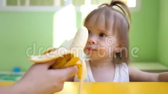 妈妈在厨房的桌子旁喂小香蕉为幼儿补充可爱的零食小子视频的预览图