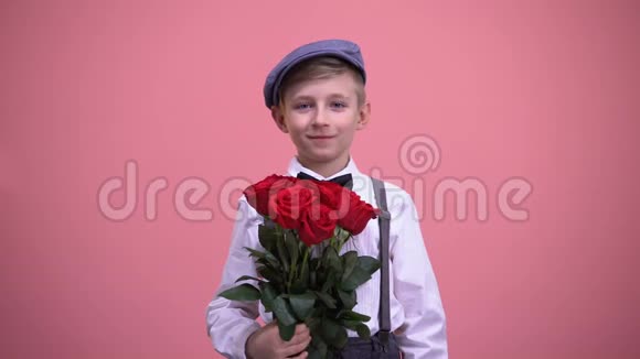 可爱的绅士男孩把一束红玫瑰送上相机情人节视频的预览图